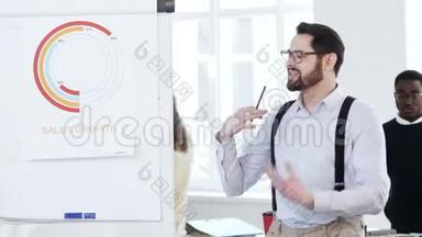 快乐成功的年轻微笑商人在现代办公会议上向工人展示<strong>挂图</strong>上的销售图。